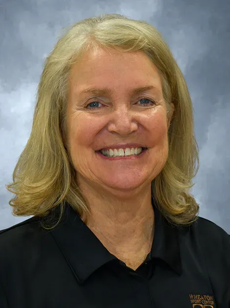Smiling woman in a black collared shirt against a blue-gray backdrop