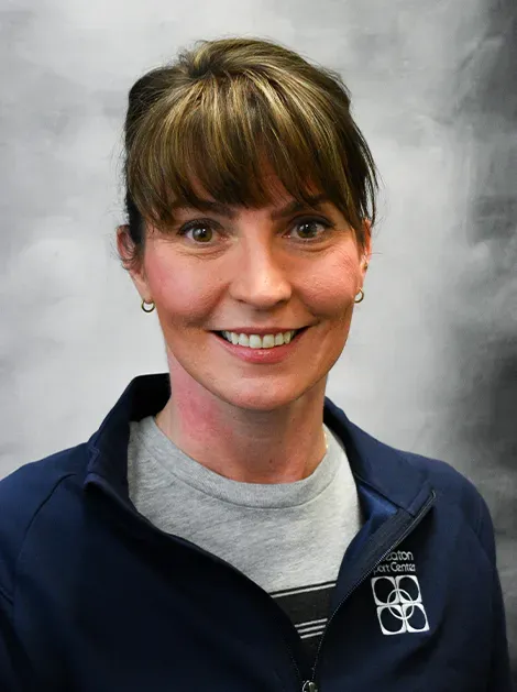 Portrait of a smiling woman in a navy jacket against a gray studio backdrop