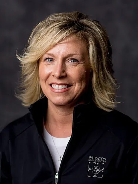 Smiling woman in a black zip-up jacket against a dark studio background