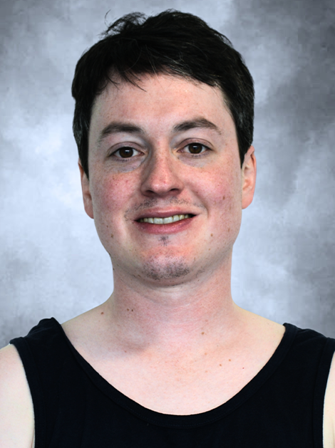 Portrait of a person in a black sleeveless top against a gray backdrop, smiling slightly