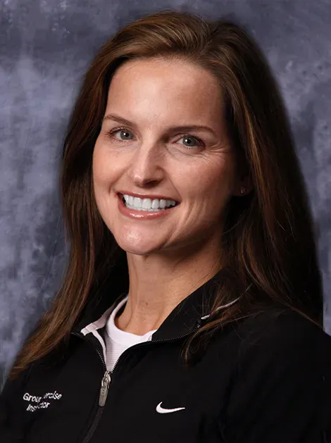 Woman smiling in a black Nike jacket against a gray studio backdrop