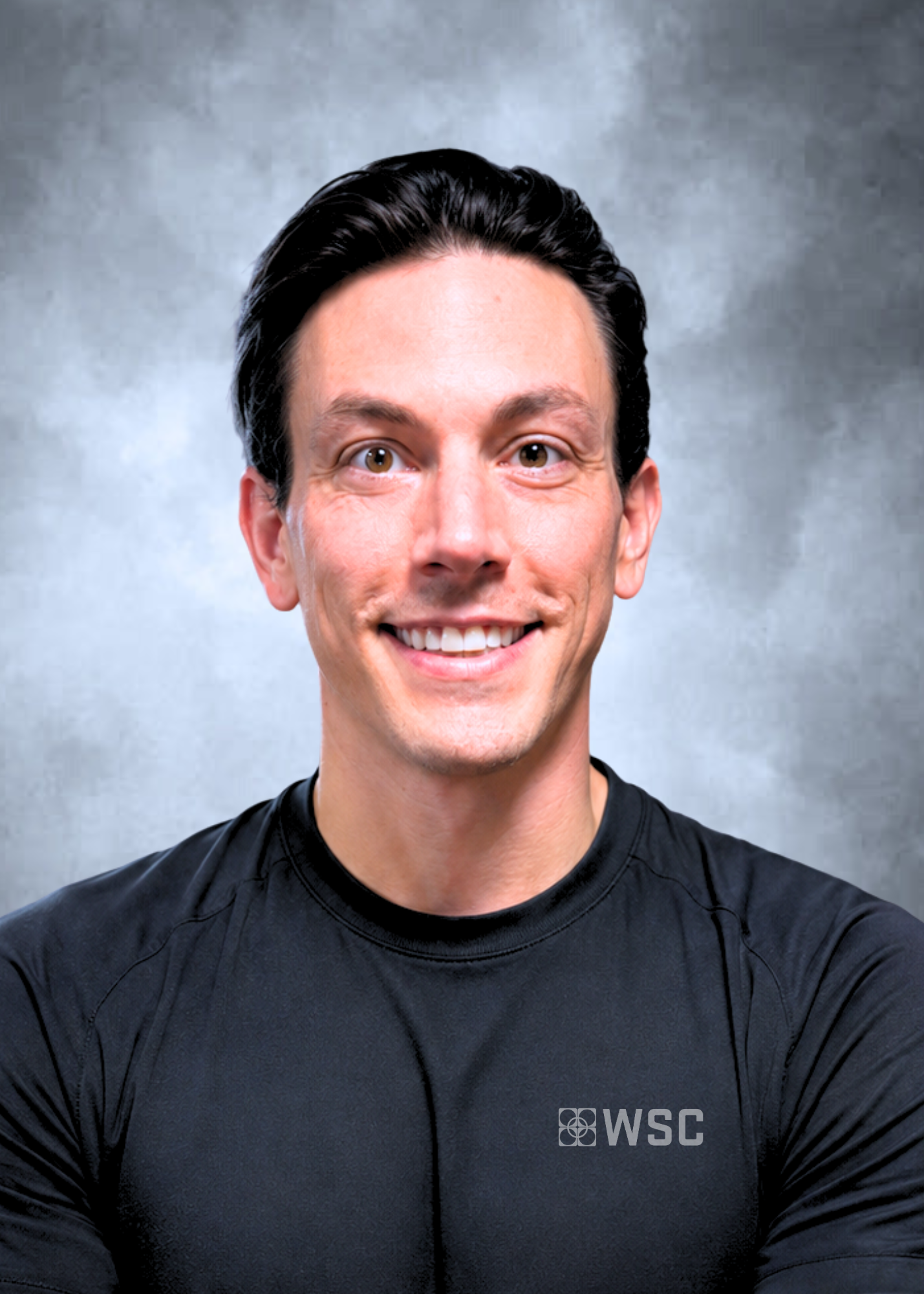 Smiling person in a black shirt against a gray studio backdrop