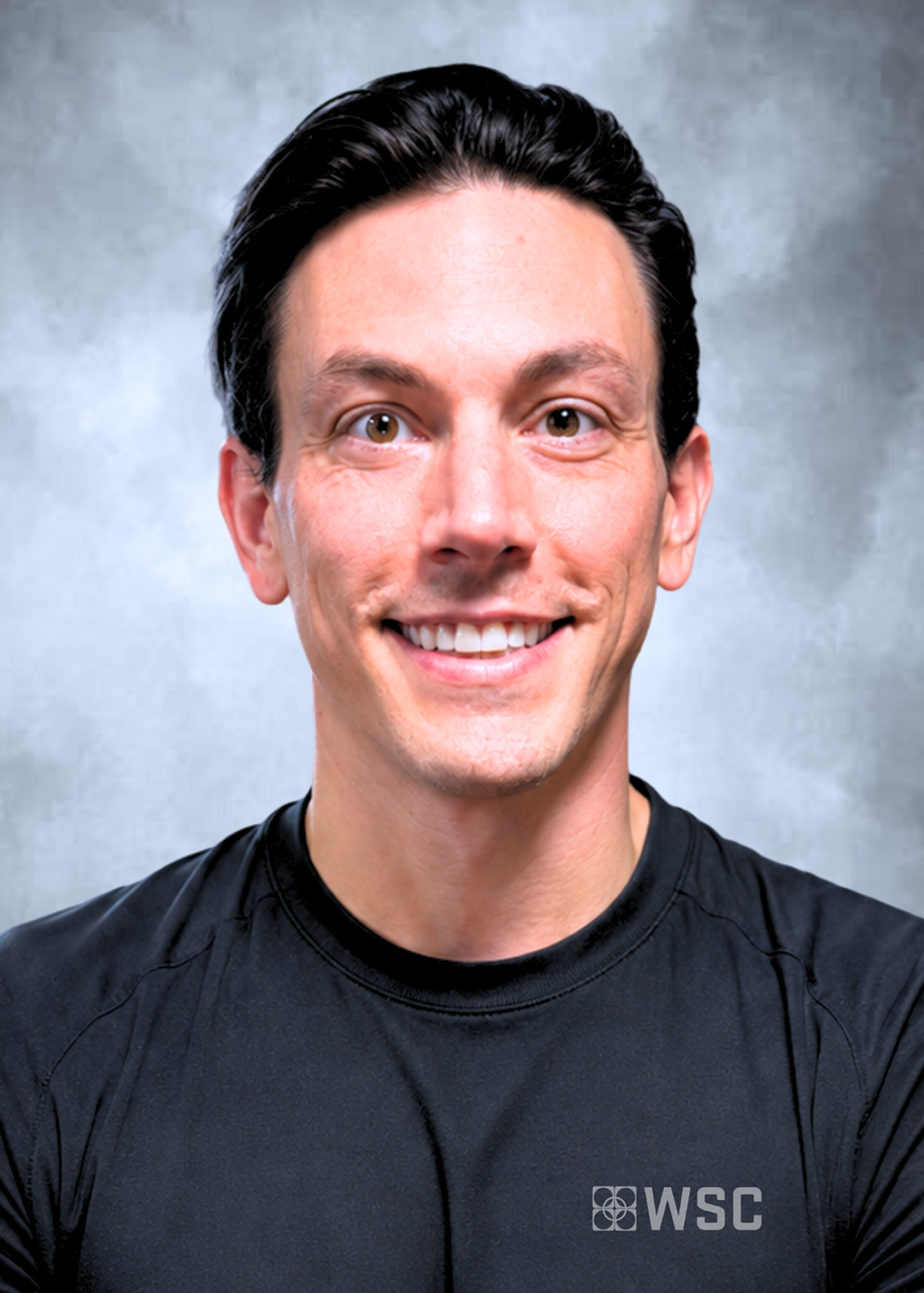 Smiling man in a black shirt against a gray studio backdrop