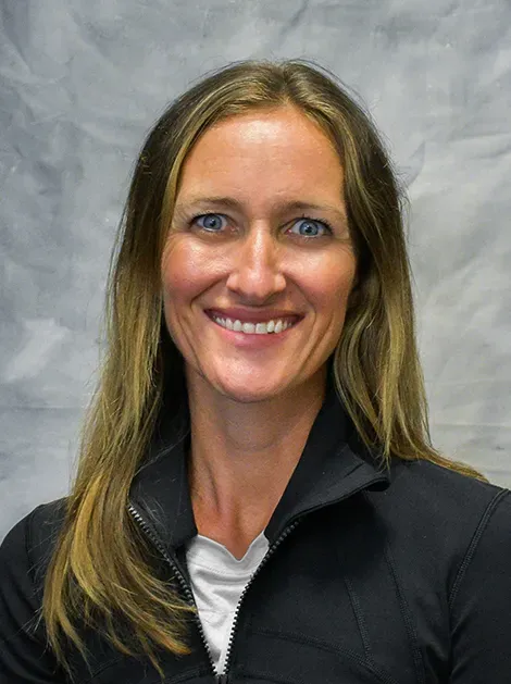 Smiling woman in a black jacket against a gray background