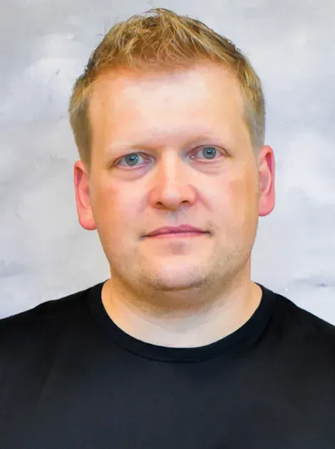 Portrait of a man in a black shirt against a light gray background