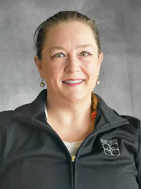 Smiling woman in a black jacket against a gray background