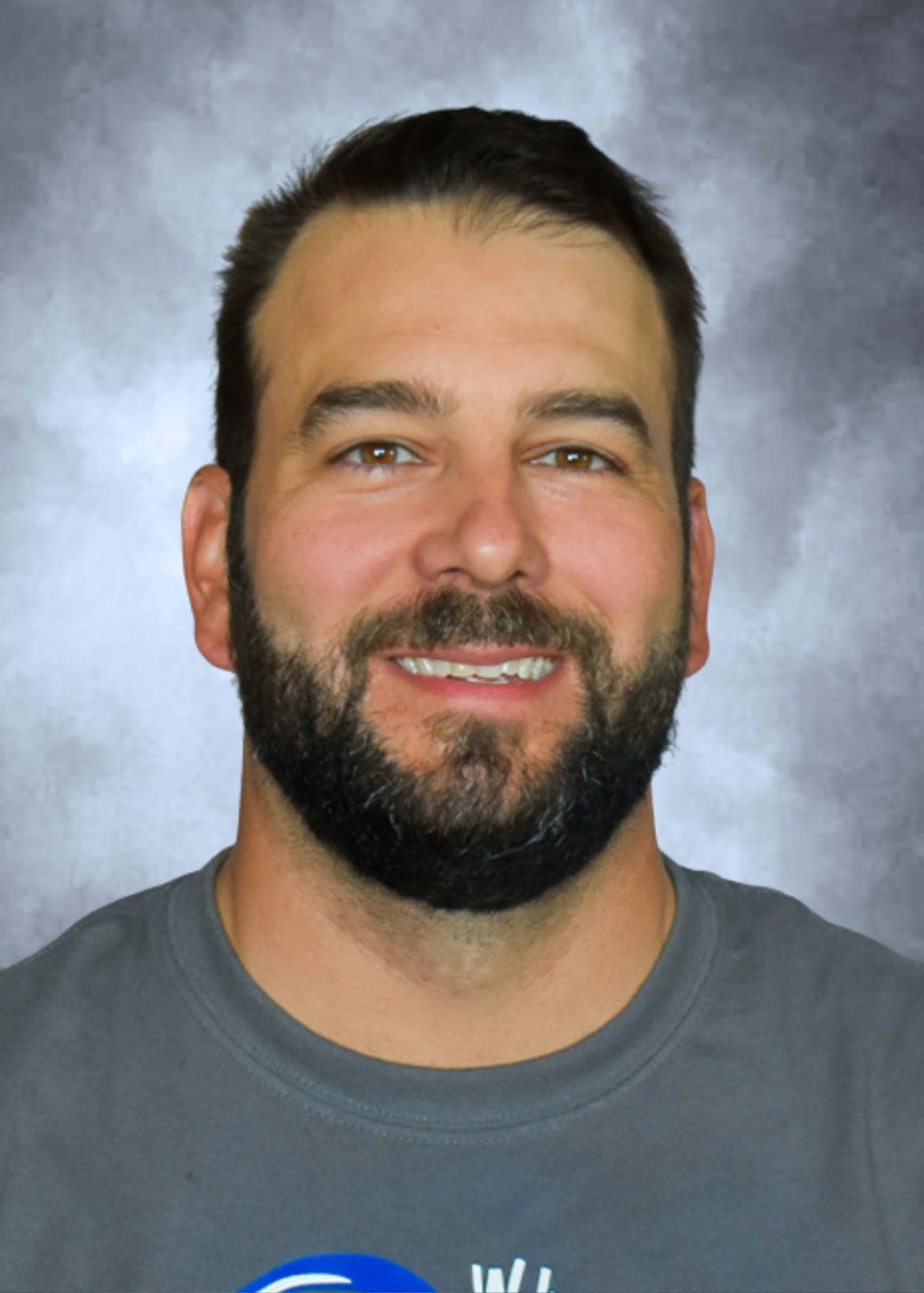 Smiling bearded man in a gray shirt against a blue-gray backdrop