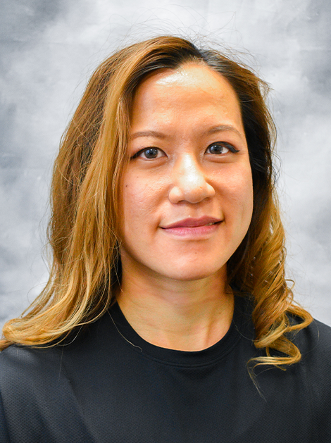 Portrait of a woman with long light brown hair wearing a black top against a gray background