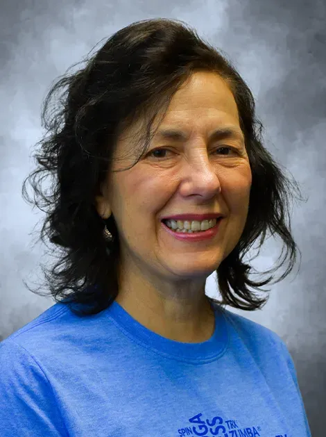 Smiling woman in a blue shirt against a gray background