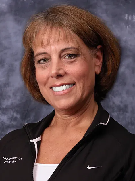 Smiling woman in black collared shirt against a gray studio backdrop