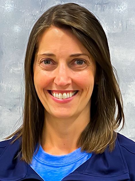 Smiling woman in a blue jacket against a gray background