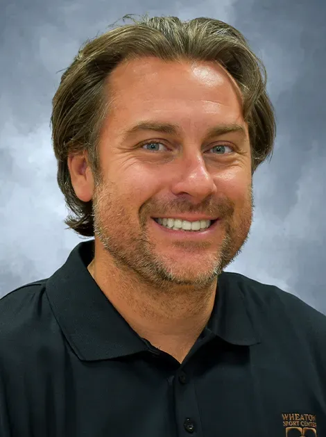 Smiling man in black polo shirt against a light blue background