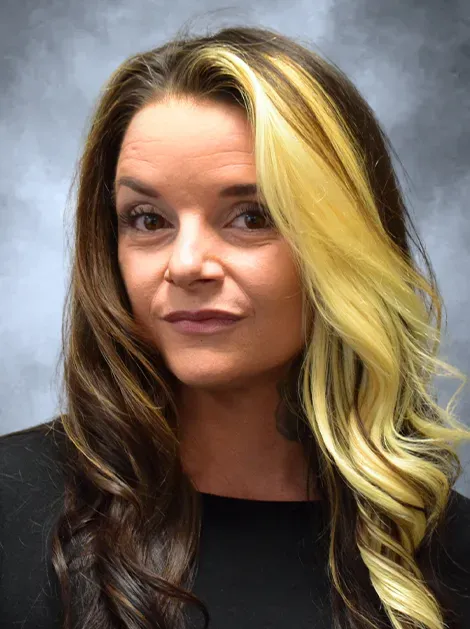Portrait of a woman with long blonde and dark hair against a gray background