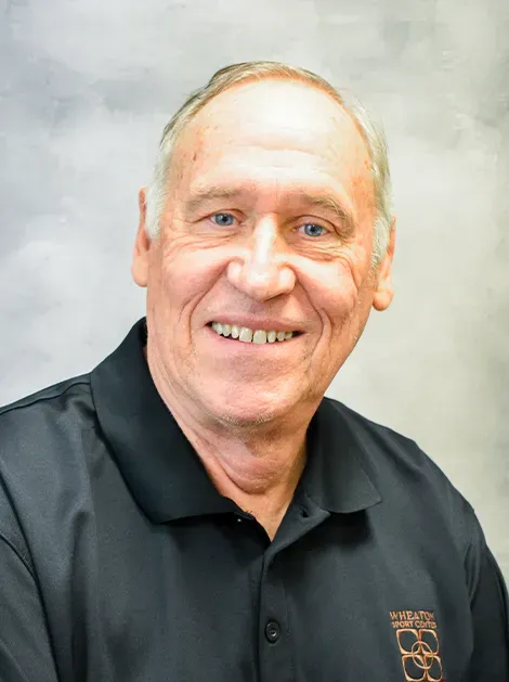 Smiling man in a black polo shirt against a light gray backdrop