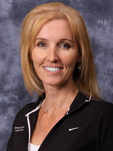 Portrait of a smiling woman in a black athletic jacket against a gray studio backdrop