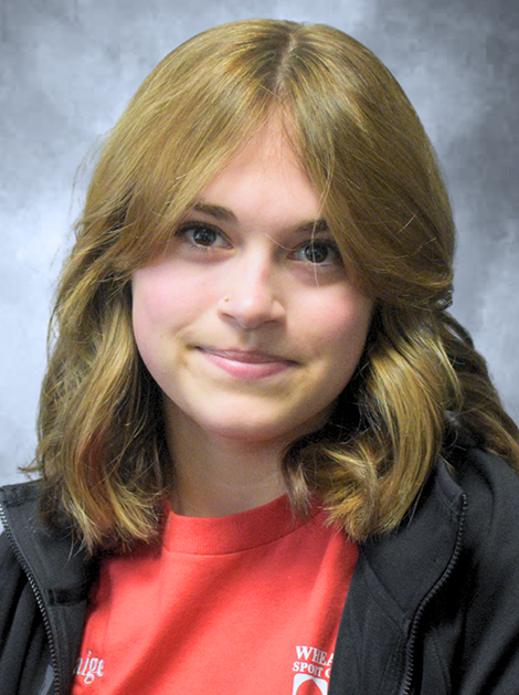 Person with shoulder-length light brown hair wearing a red shirt and dark jacket, smiling at the camera.