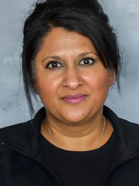 Studio headshot of a smiling person in a black top against a gray background