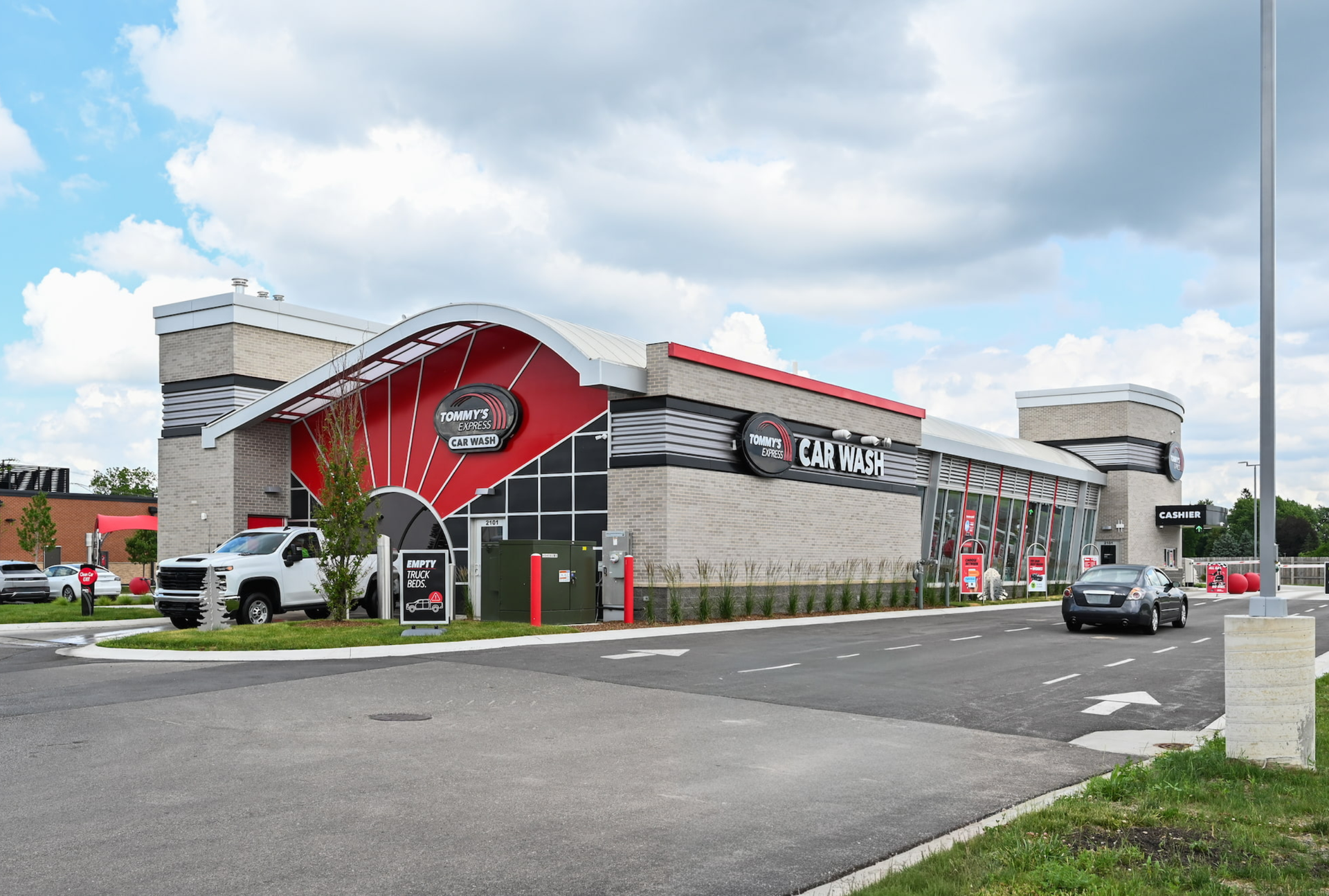 Modern stone-and-red commercial building with U-Haul signage beside a road under a cloudy sky