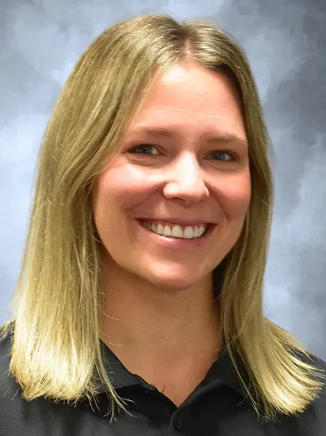 Smiling blonde woman in a black shirt against a light blue background