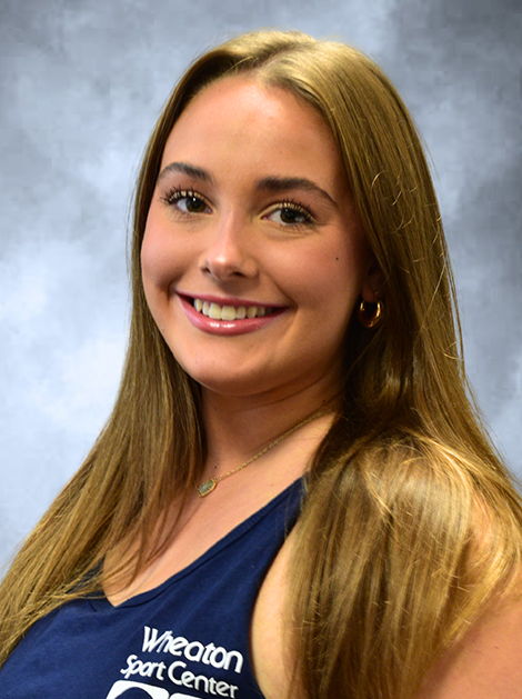 Smiling person in a navy top against a gray studio backdrop