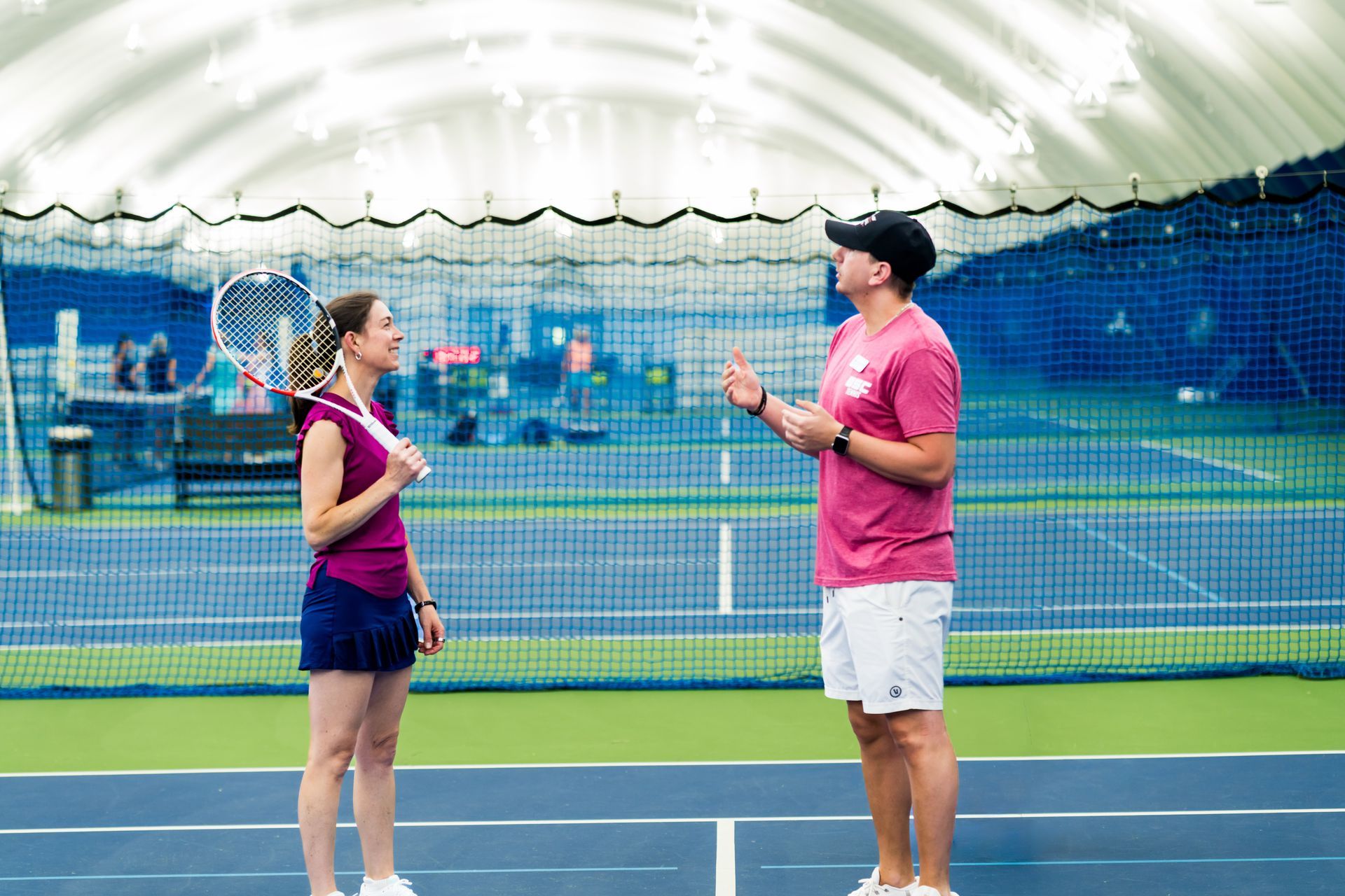 Two tennis players talking on an indoor court under a white dome