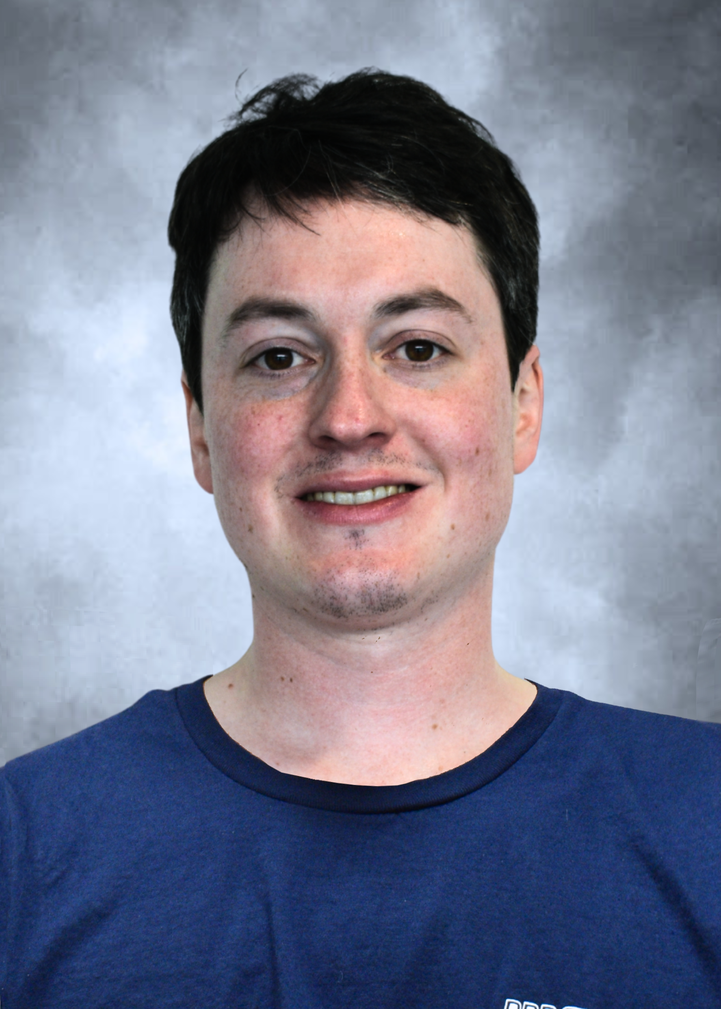 Head-and-shoulders portrait of a person in a black top against a gray backdrop, smiling slightly.