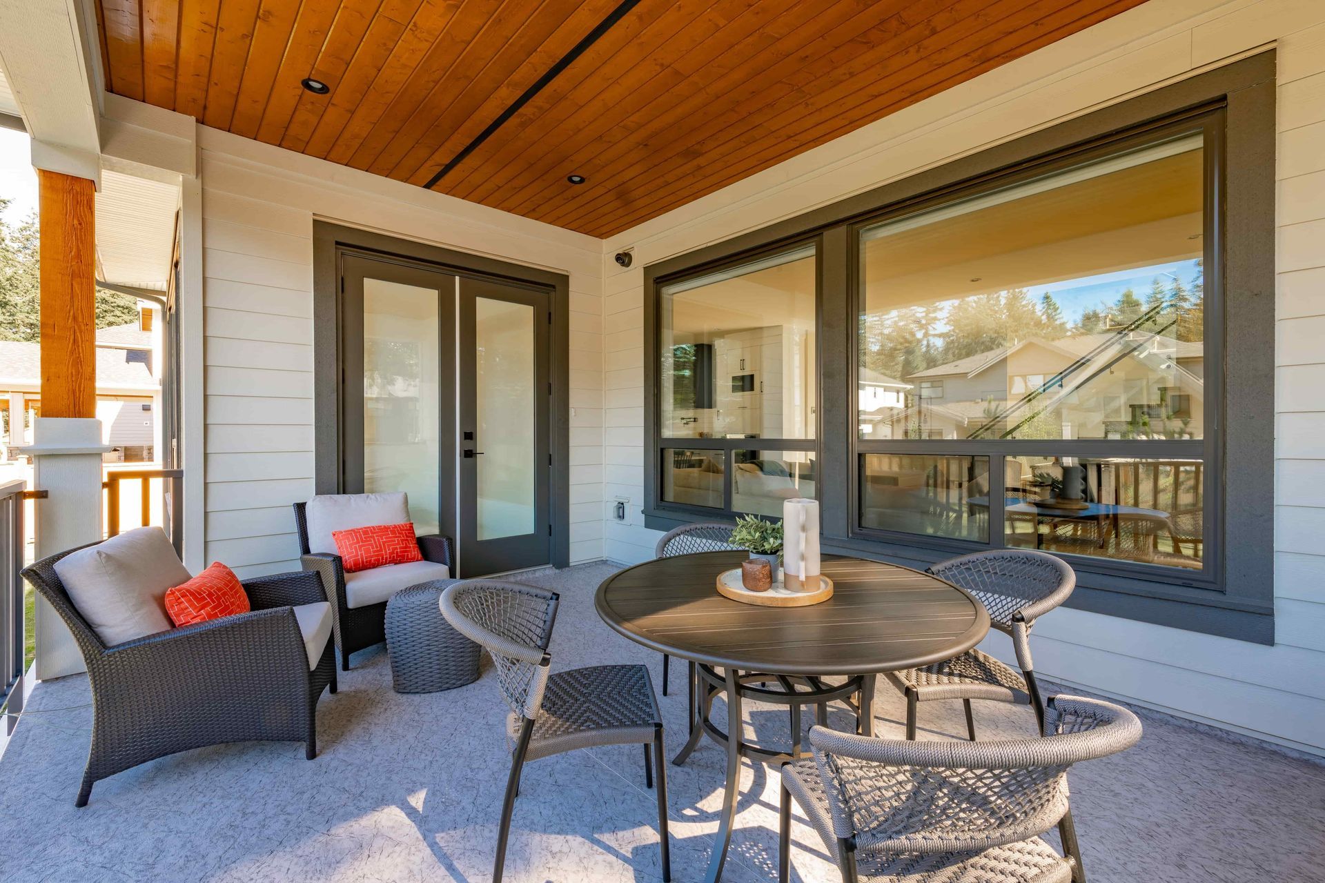 Covered patio with wicker seating, round table, and large sliding glass doors overlooking a view.