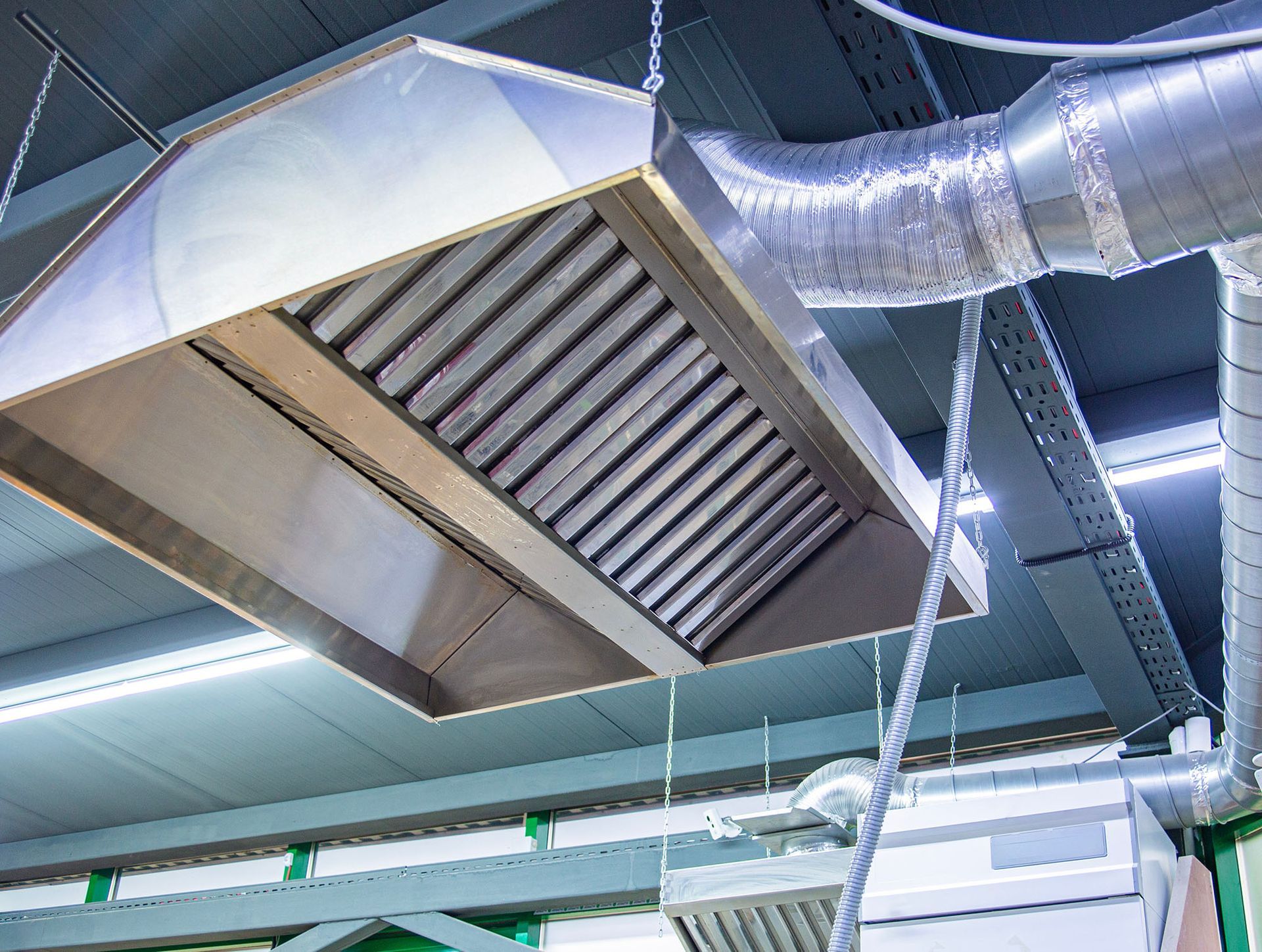 Stainless steel ventilation hood and ducting on a factory ceiling