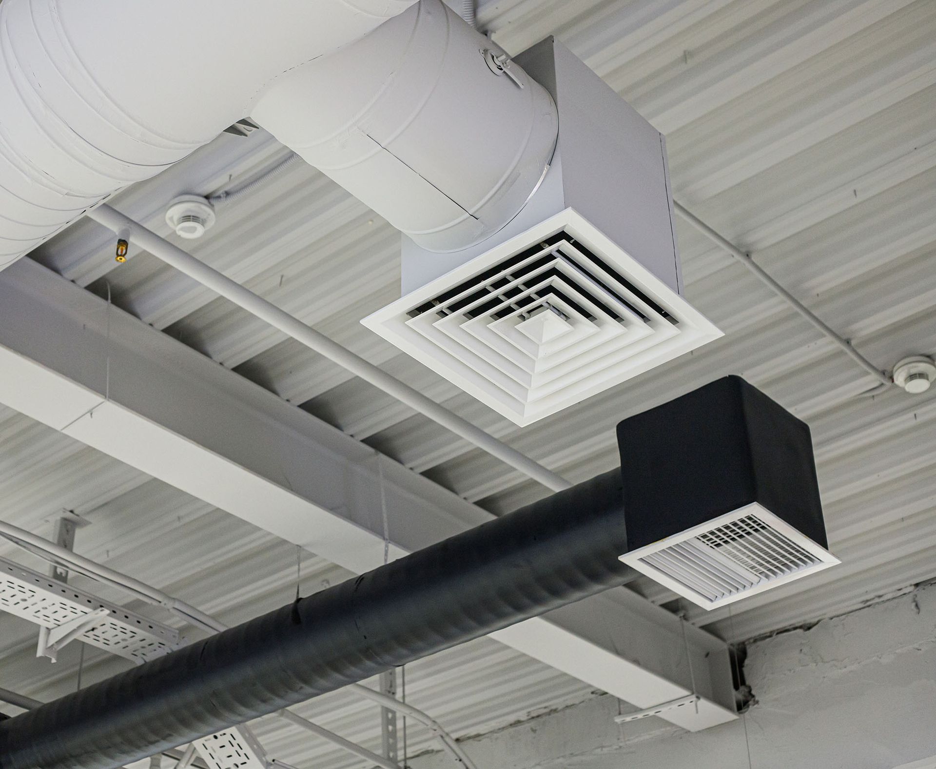 Ceiling with exposed ducts and vents, including a large black duct and white HVAC grilles.