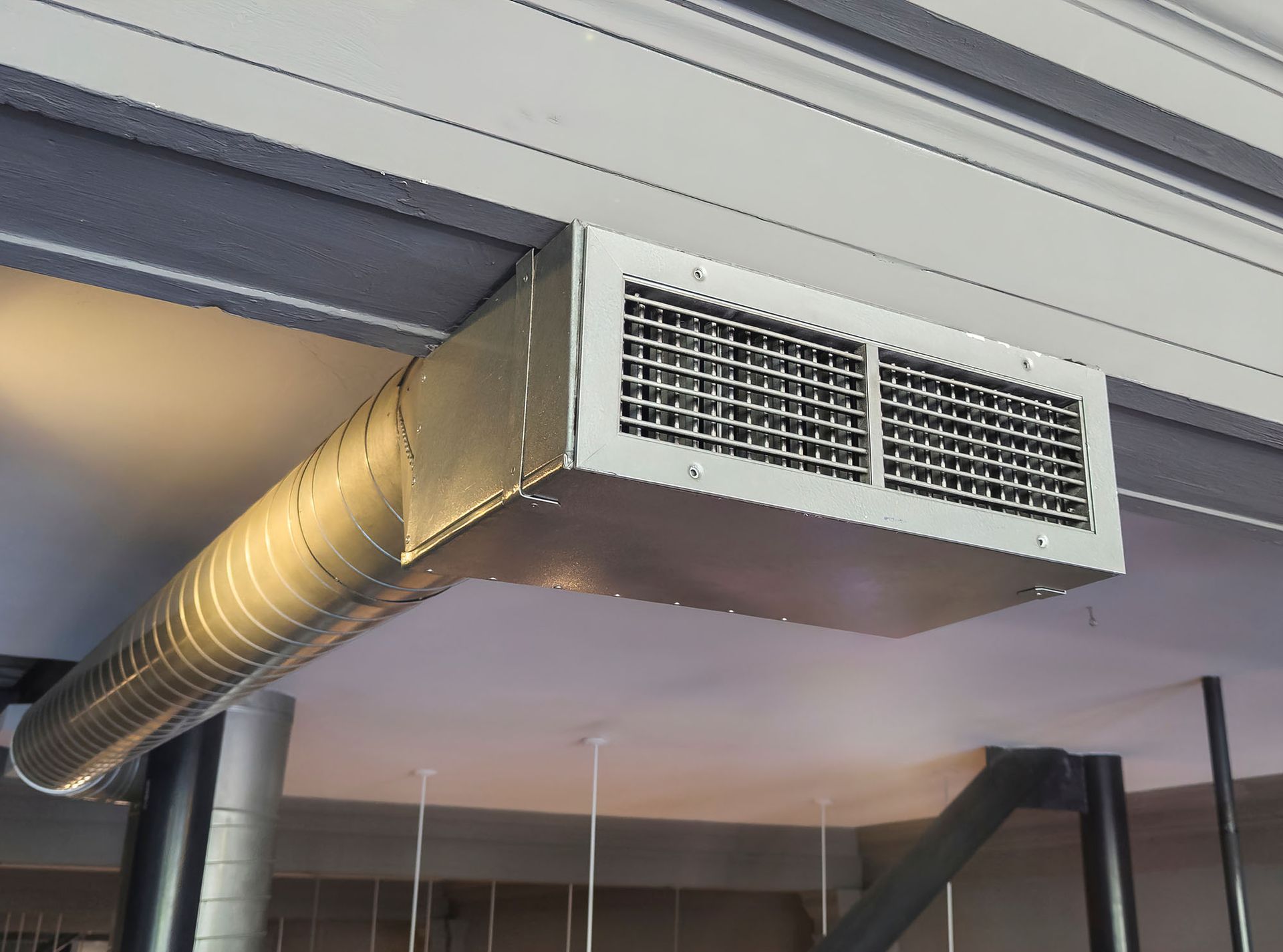 Ceiling-mounted HVAC duct with rectangular vent above an indoor room
