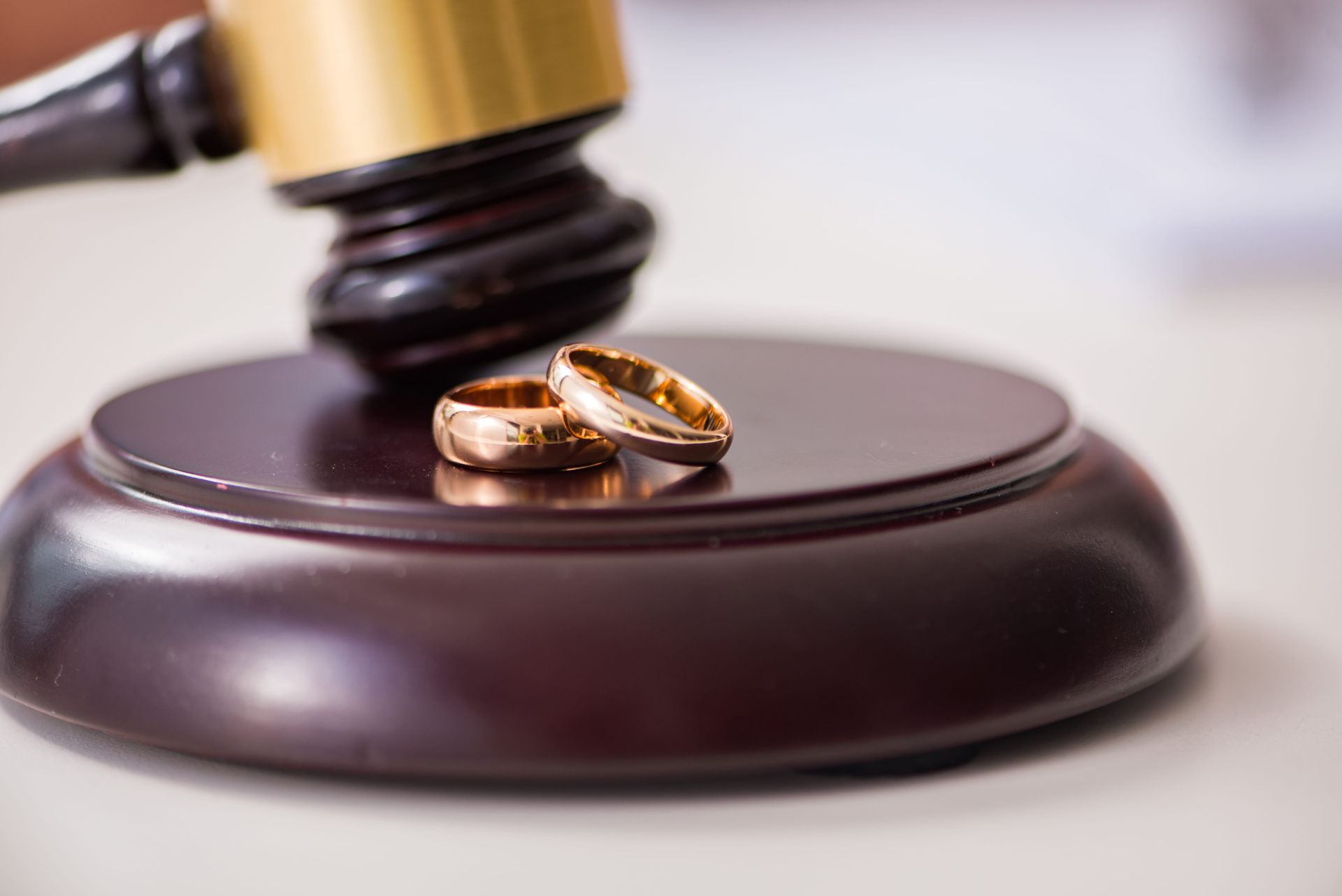 Wedding rings on a wooden judge’s gavel base
