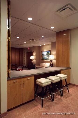 Empty hotel lounge with a wooden counter, two stools, and warm recessed lighting.