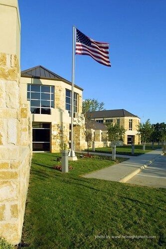 American flag on a pole outside a beige stone building on a sunny day