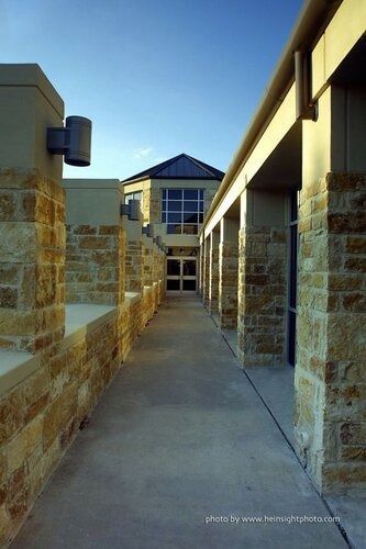 Narrow stone walkway between buildings leading to a blue-roofed structure in the distance