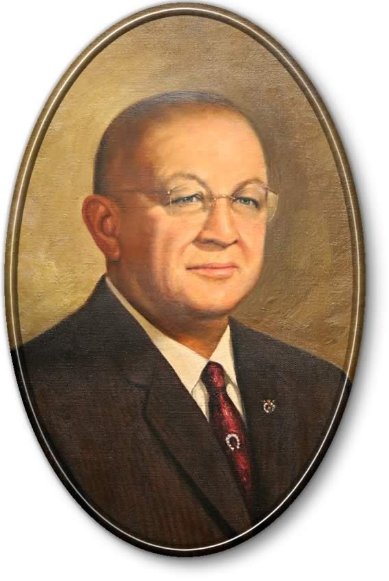 Portrait of a man in a dark suit and tie, wearing glasses, against a gold oval background