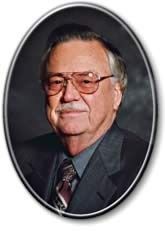 Portrait of an older man in a dark suit and tie, wearing glasses, framed in an oval border