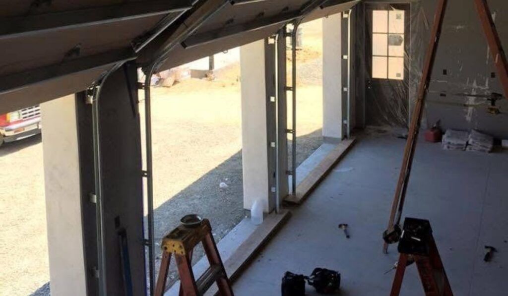 Interior under construction with open glass wall, ladder, and tools on the floor.