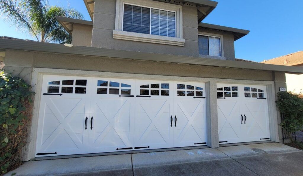 White three-car garage with arched windows on a beige house exterior