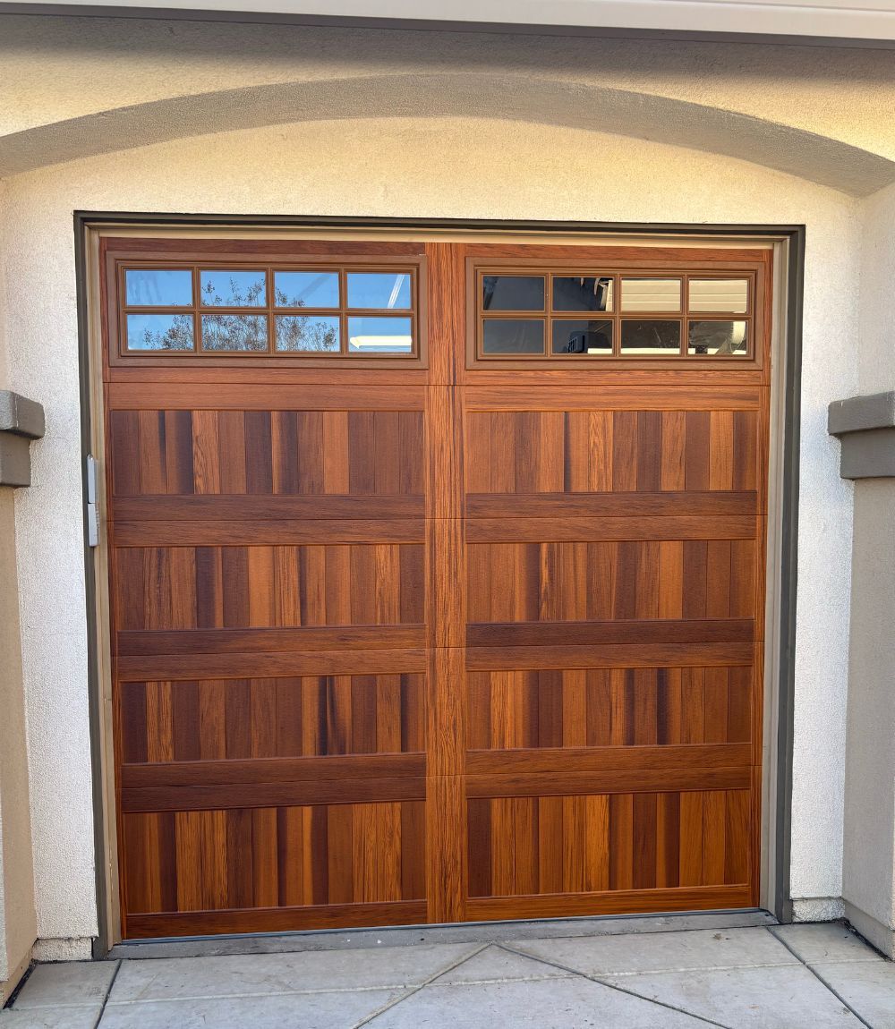 Wooden double garage doors with small blue-glass windows beneath a stucco archway