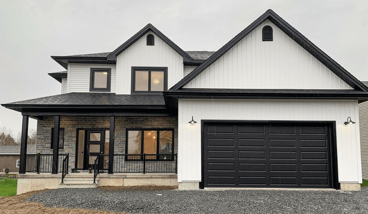 Modern two-story white house with black trim, front porch, and double garage under construction or newly built