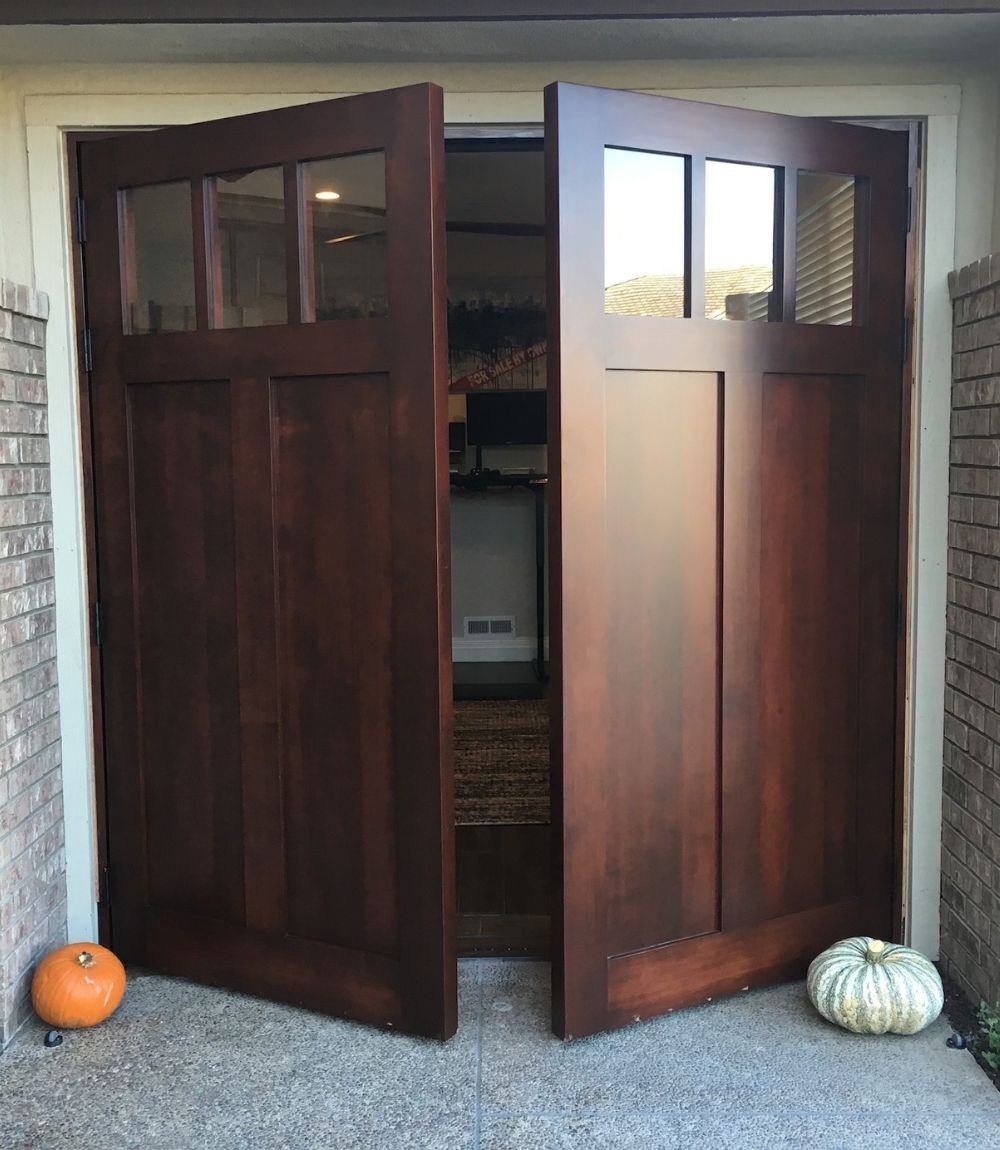 Open wooden double doors with pumpkins at the threshold, revealing a room inside.