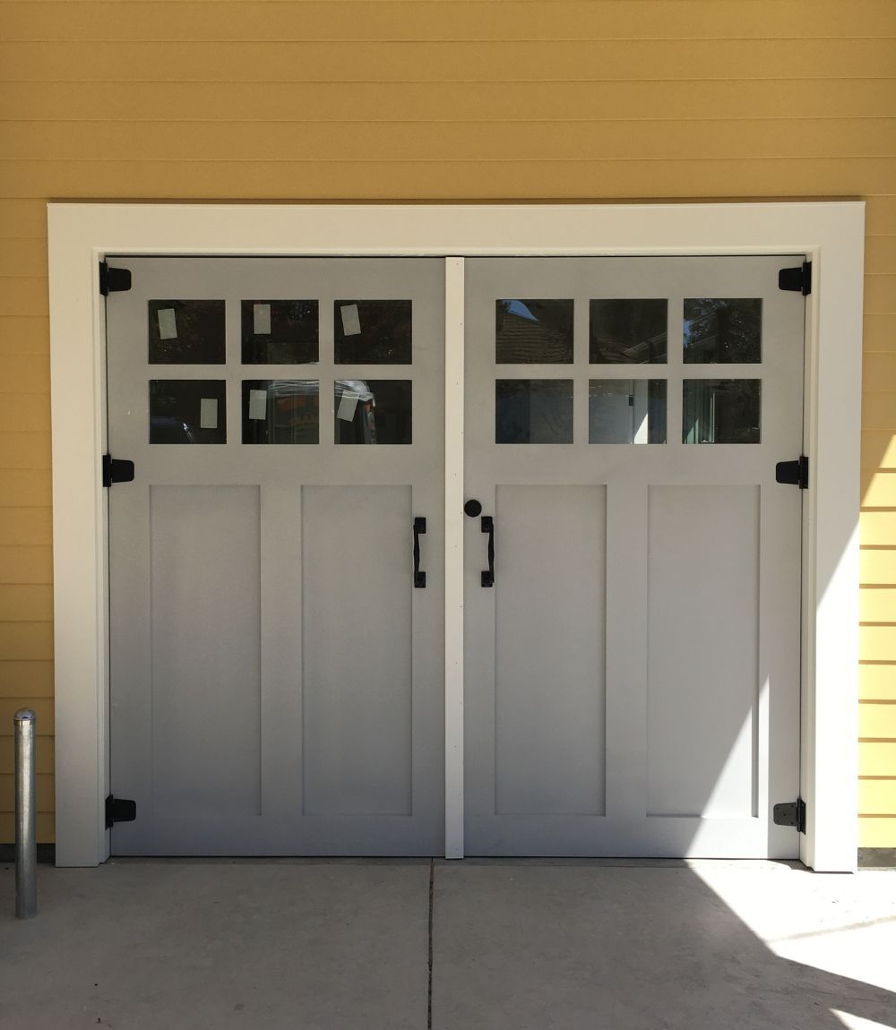 Closed white double doors with small windows on a beige building exterior