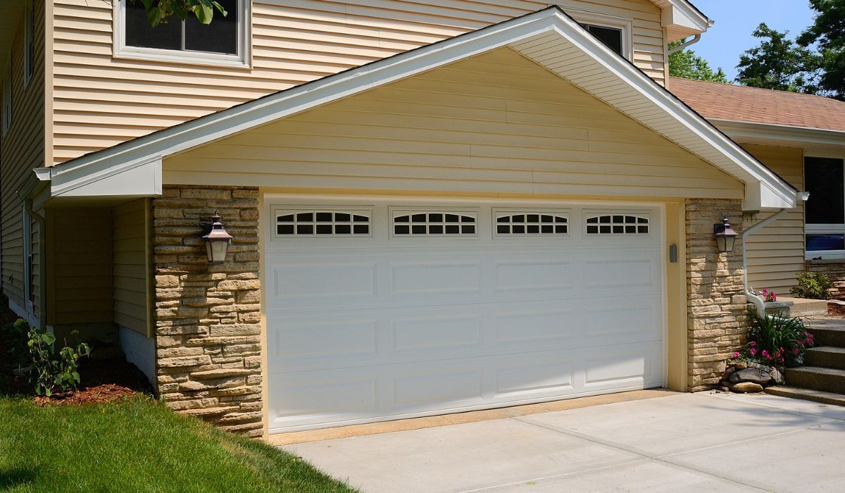 Suburban house with a white two-car garage door and stone siding