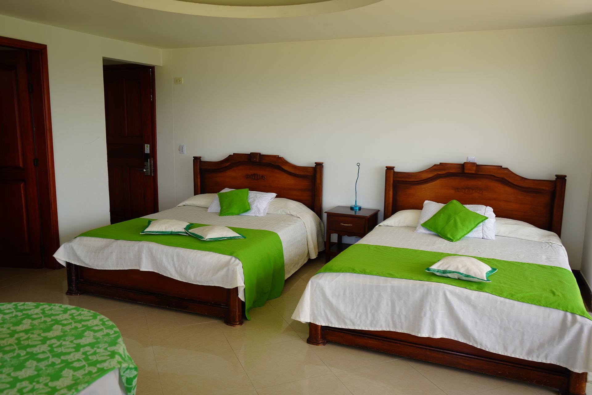 Dos camas en una habitación de hotel con sábanas y almohadas verdes.