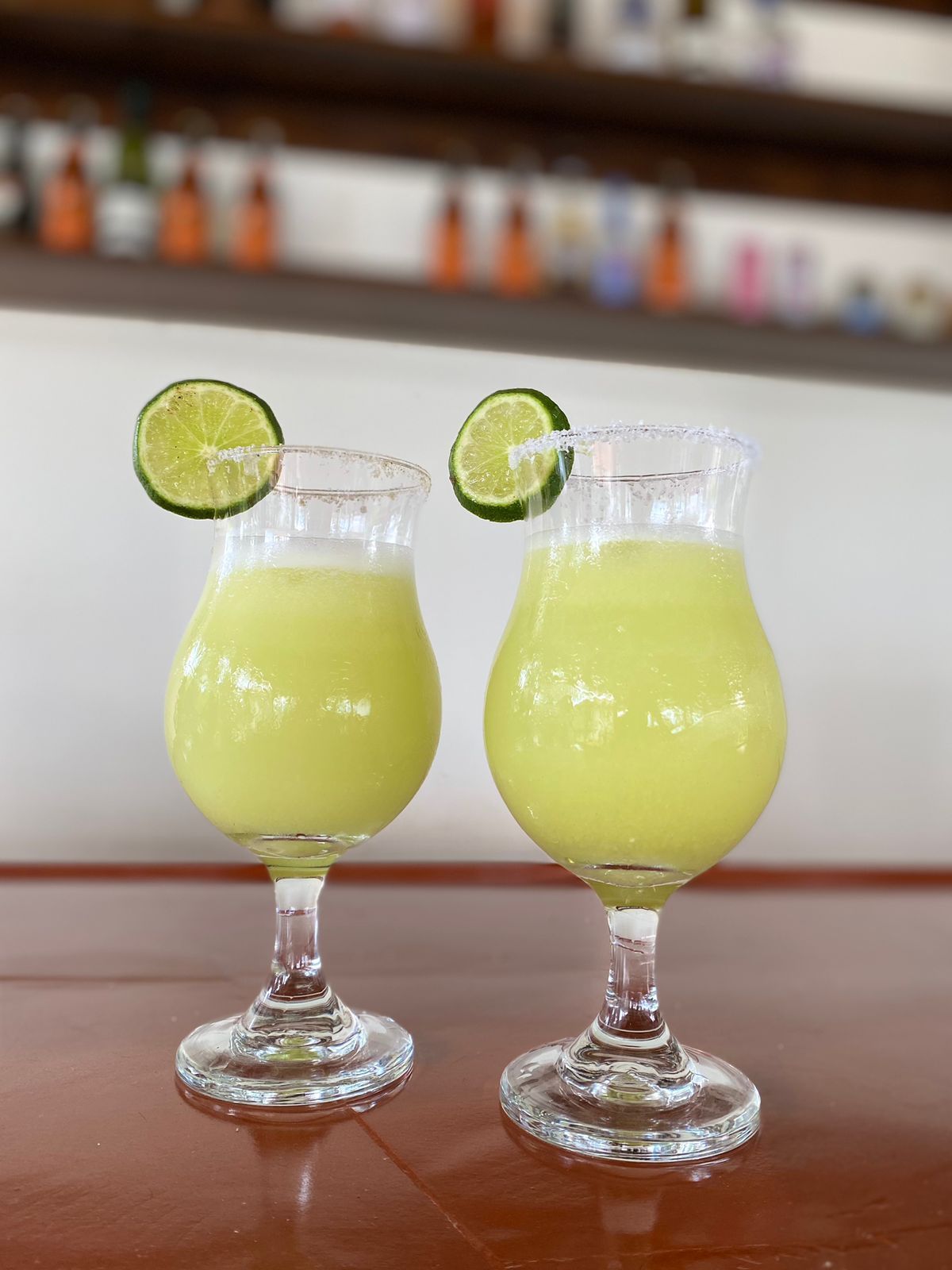 Dos vasos de limonada con rodajas de lima sobre una mesa de madera.