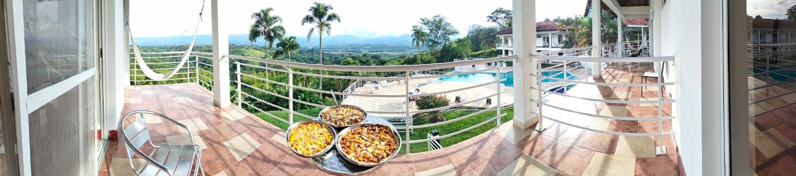 Un balcón con vista a una piscina y palmeras.