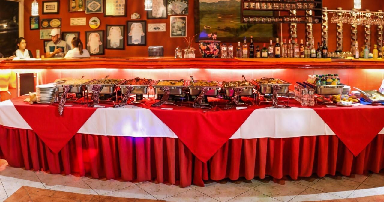 Una mesa de buffet larga con un mantel rojo y blanco.