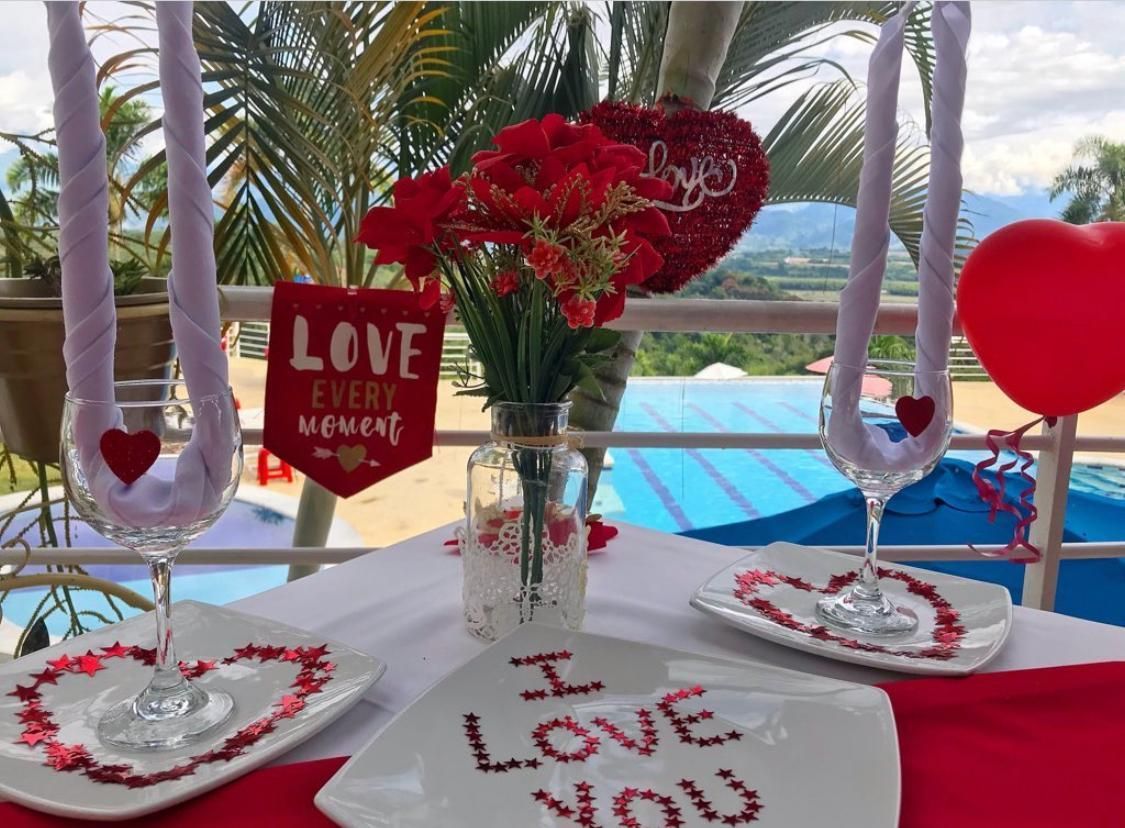 Una mesa con platos, vasos, un jarrón con flores y un cartel que dice