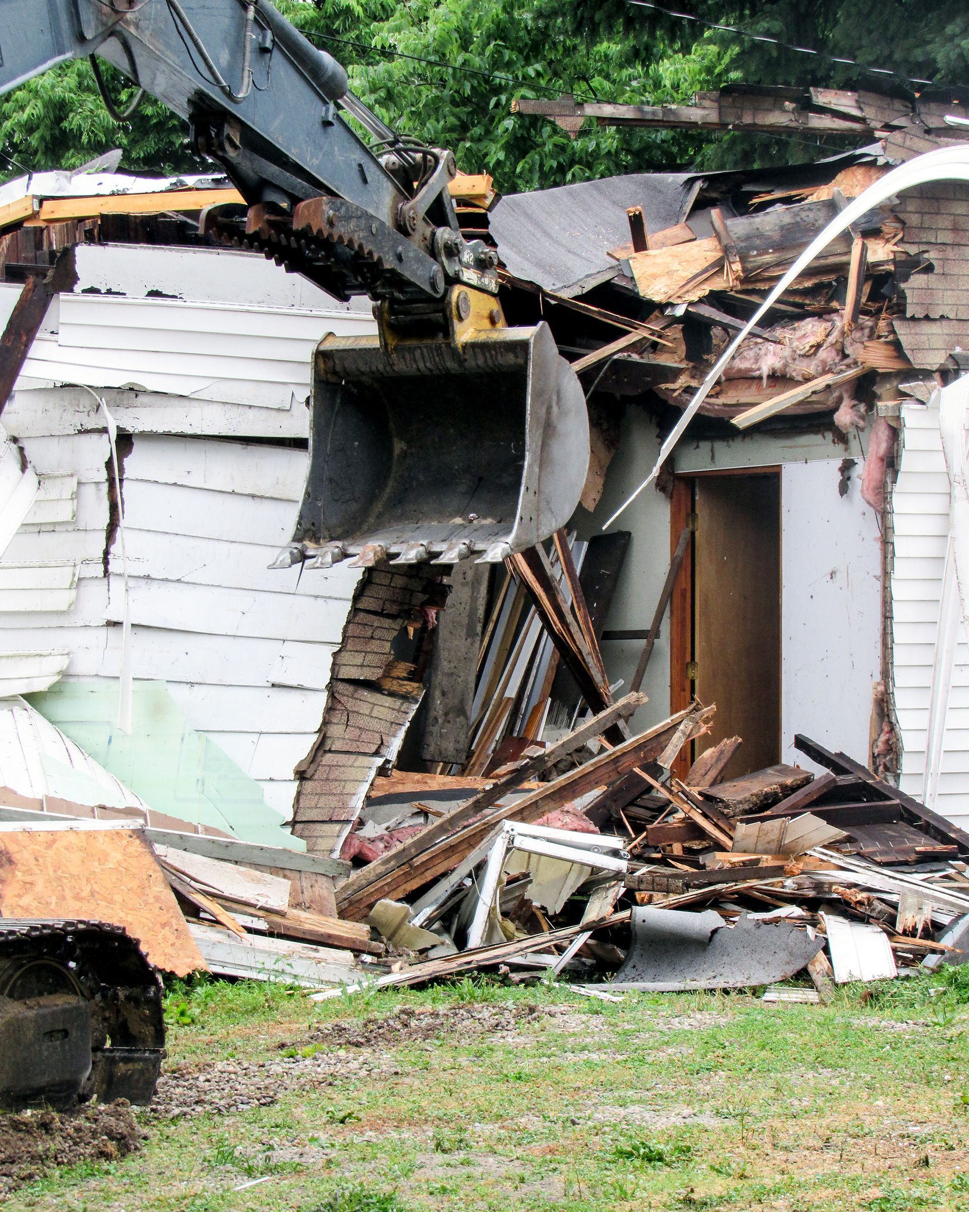 a house is being demolished by a bulldozer .