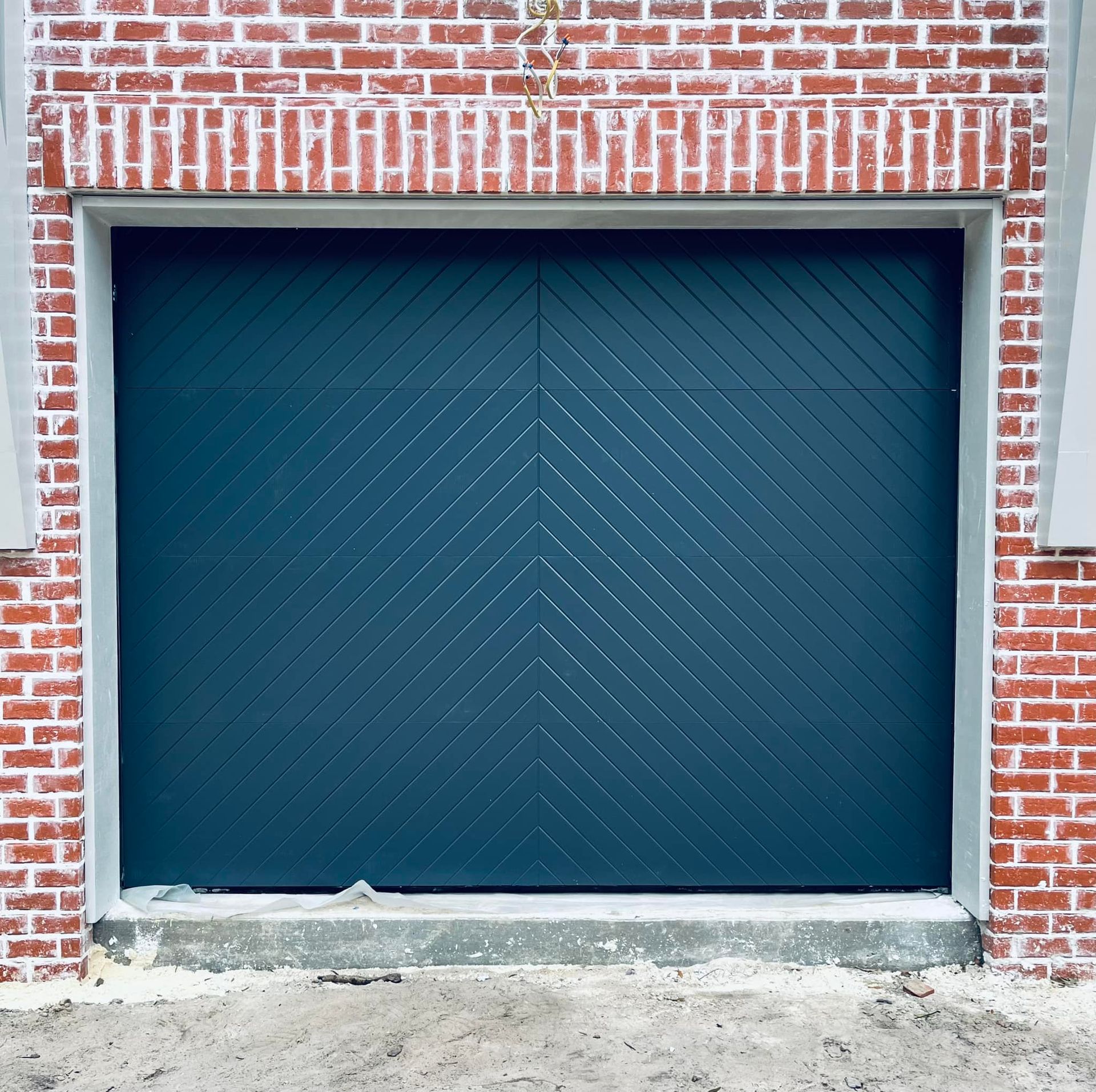 Blue garage door set in a red brick wall with a concrete threshold